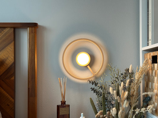 Pure MDRN ORA sconce in Sand color on a bedroom wall next to a bed.