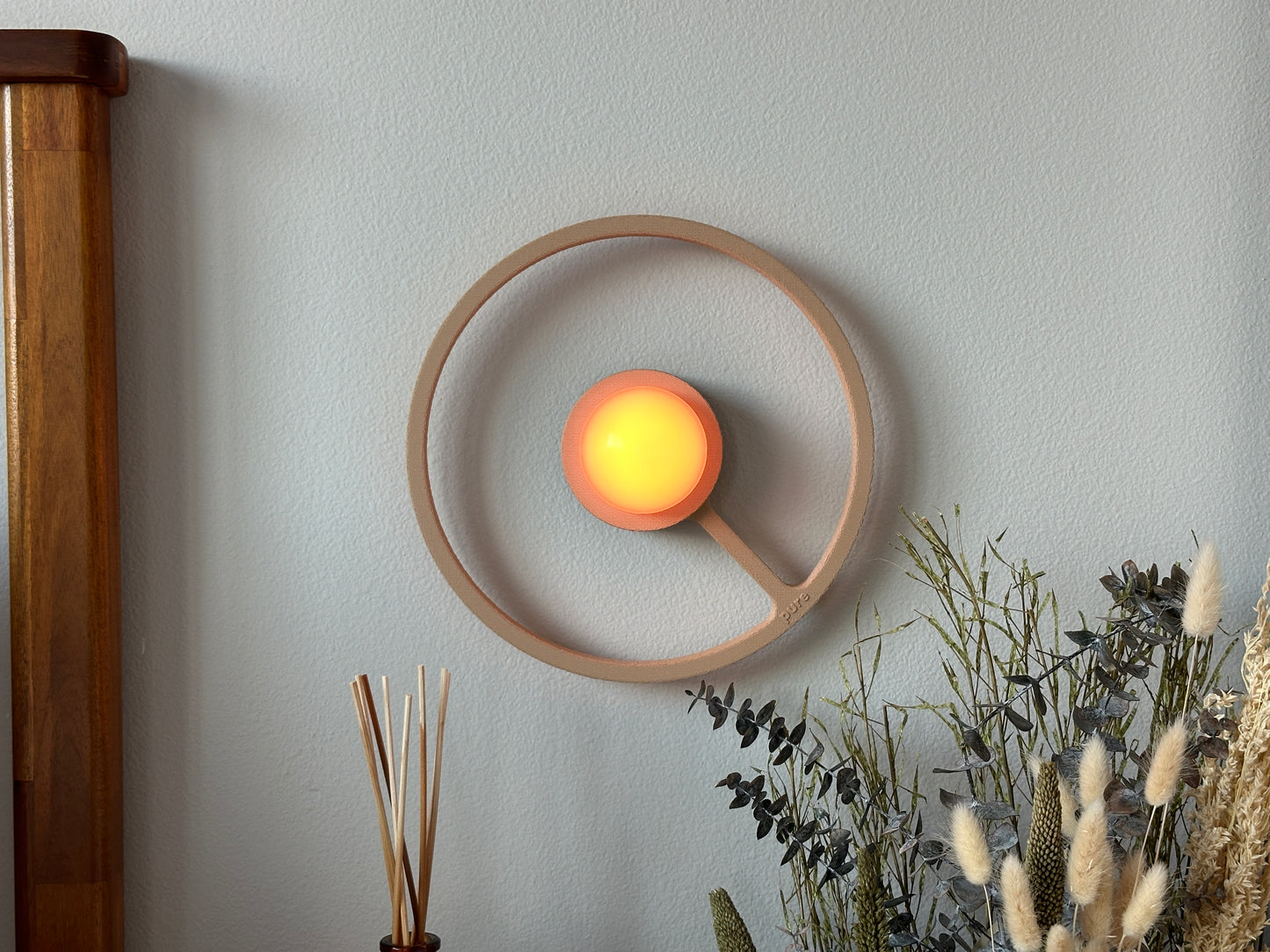 Pure MDRN ORA sconce in Sand color on a bedroom wall next to a bed.