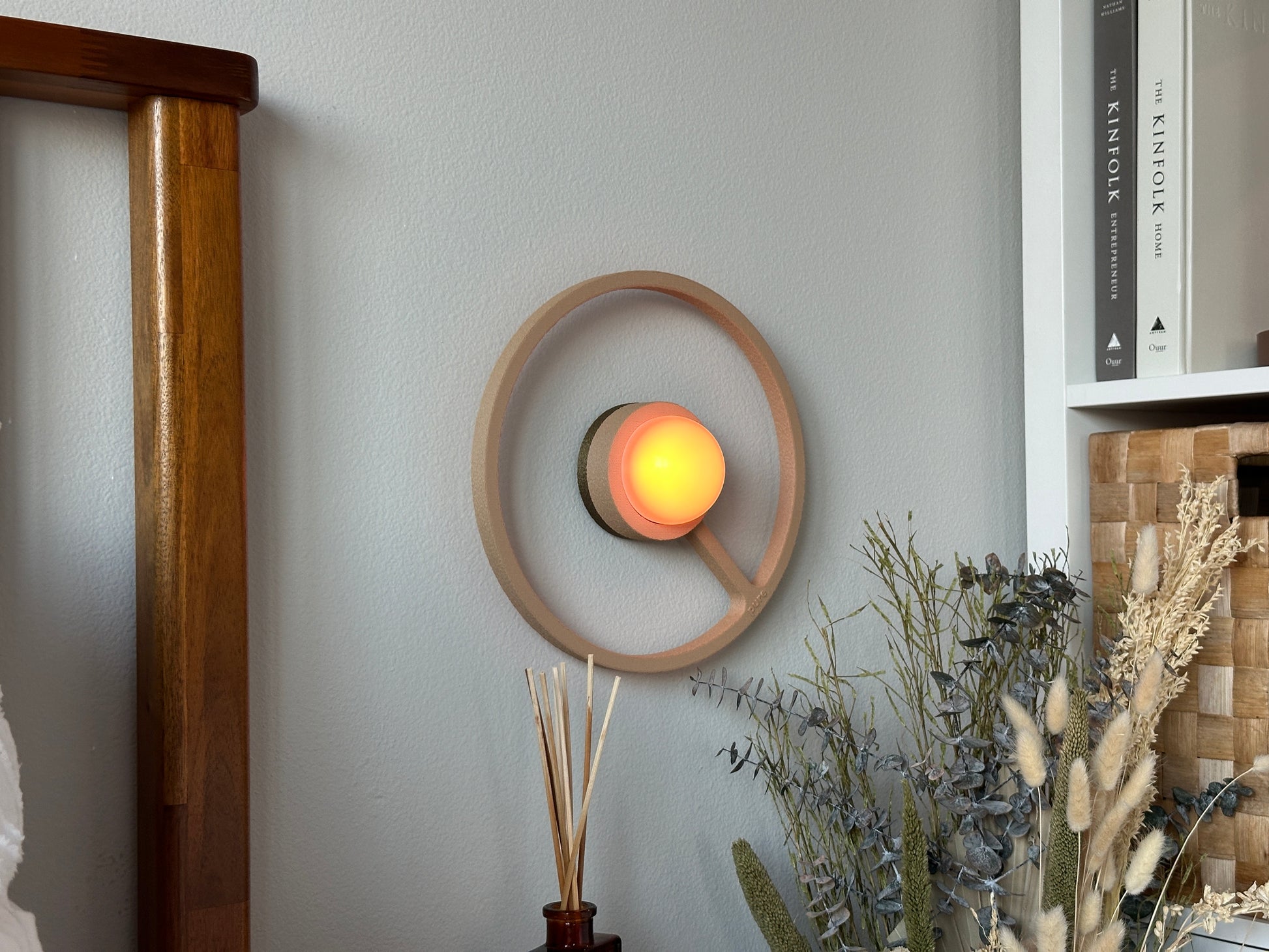 Pure MDRN ORA sconce in Sand color on a bedroom wall next to a bed.