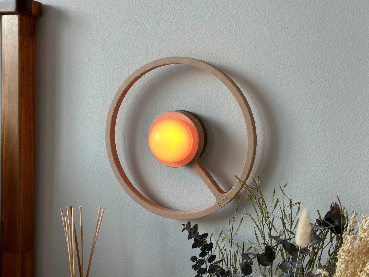 Pure MDRN ORA sconce in Sand color on a bedroom wall next to a bed.