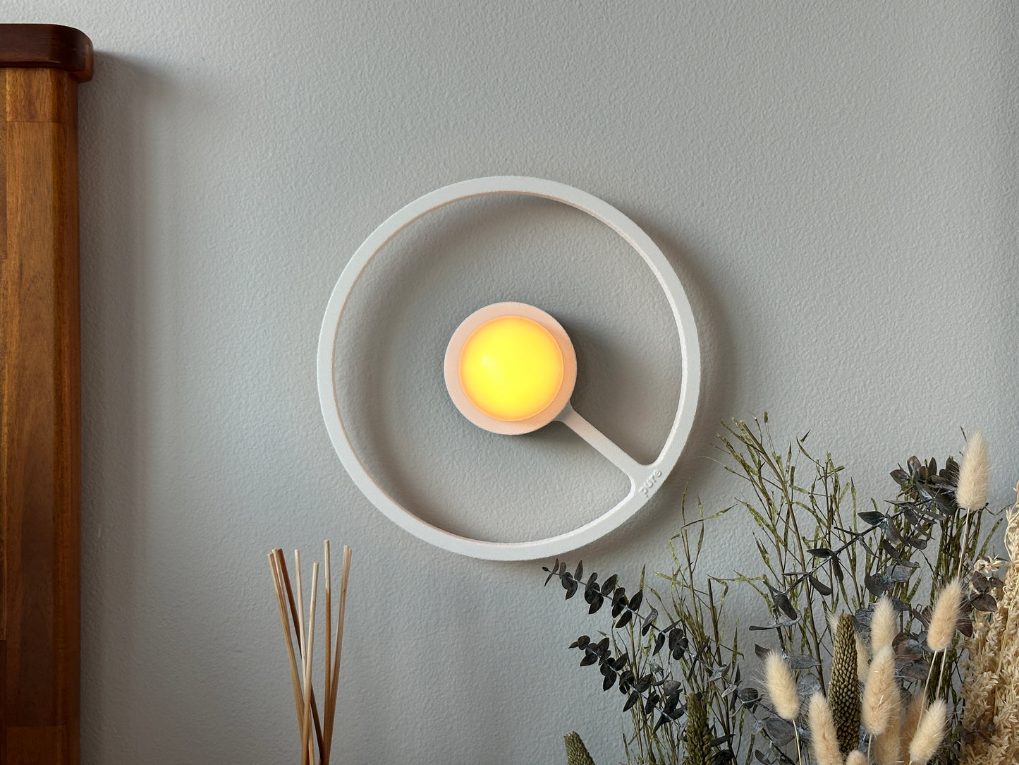 Pure MDRN ORA sconce in Blanco color on a bedroom wall next to a bed.