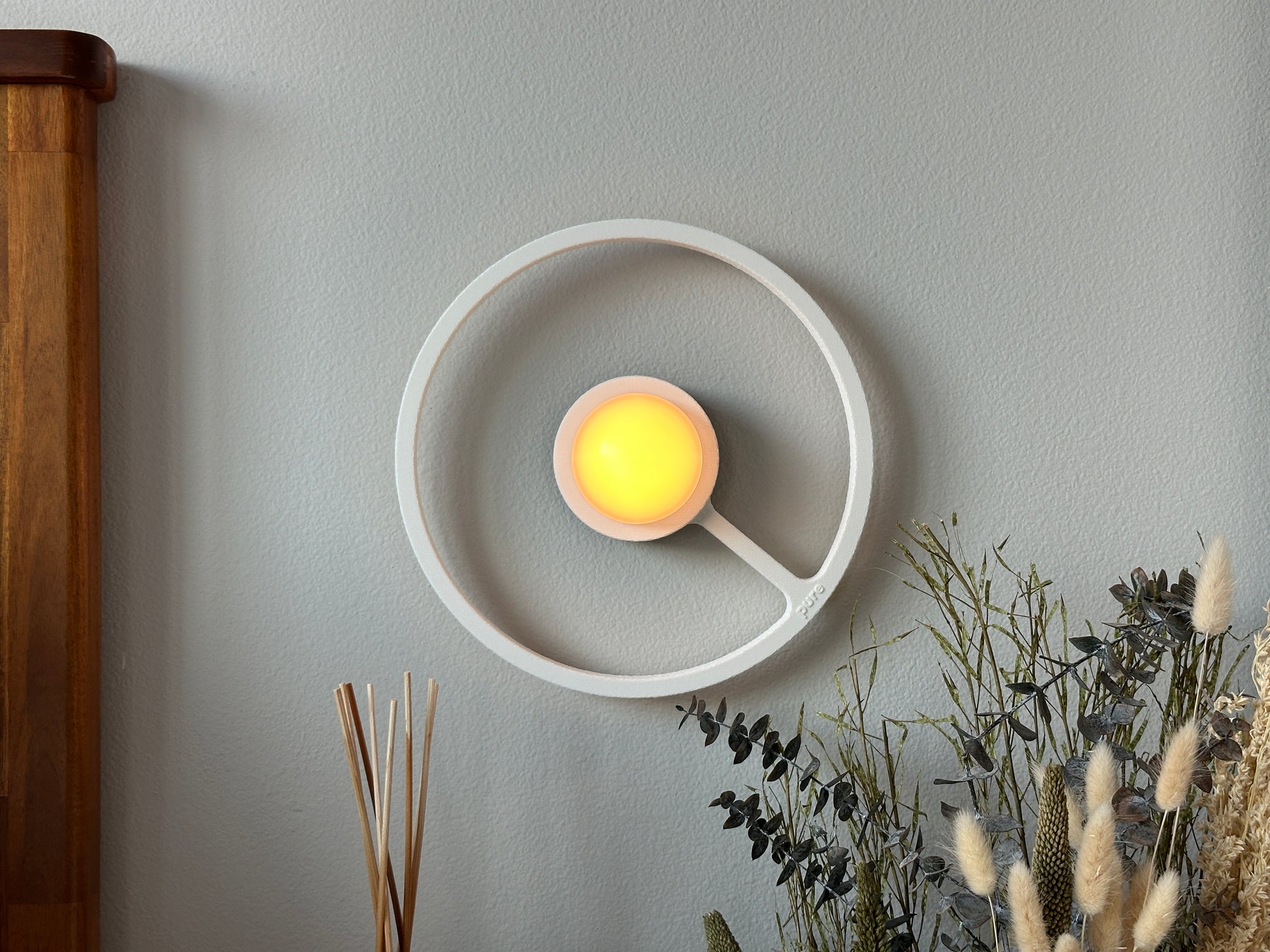 Pure MDRN ORA sconce in Blanco color on a bedroom wall next to a bed.