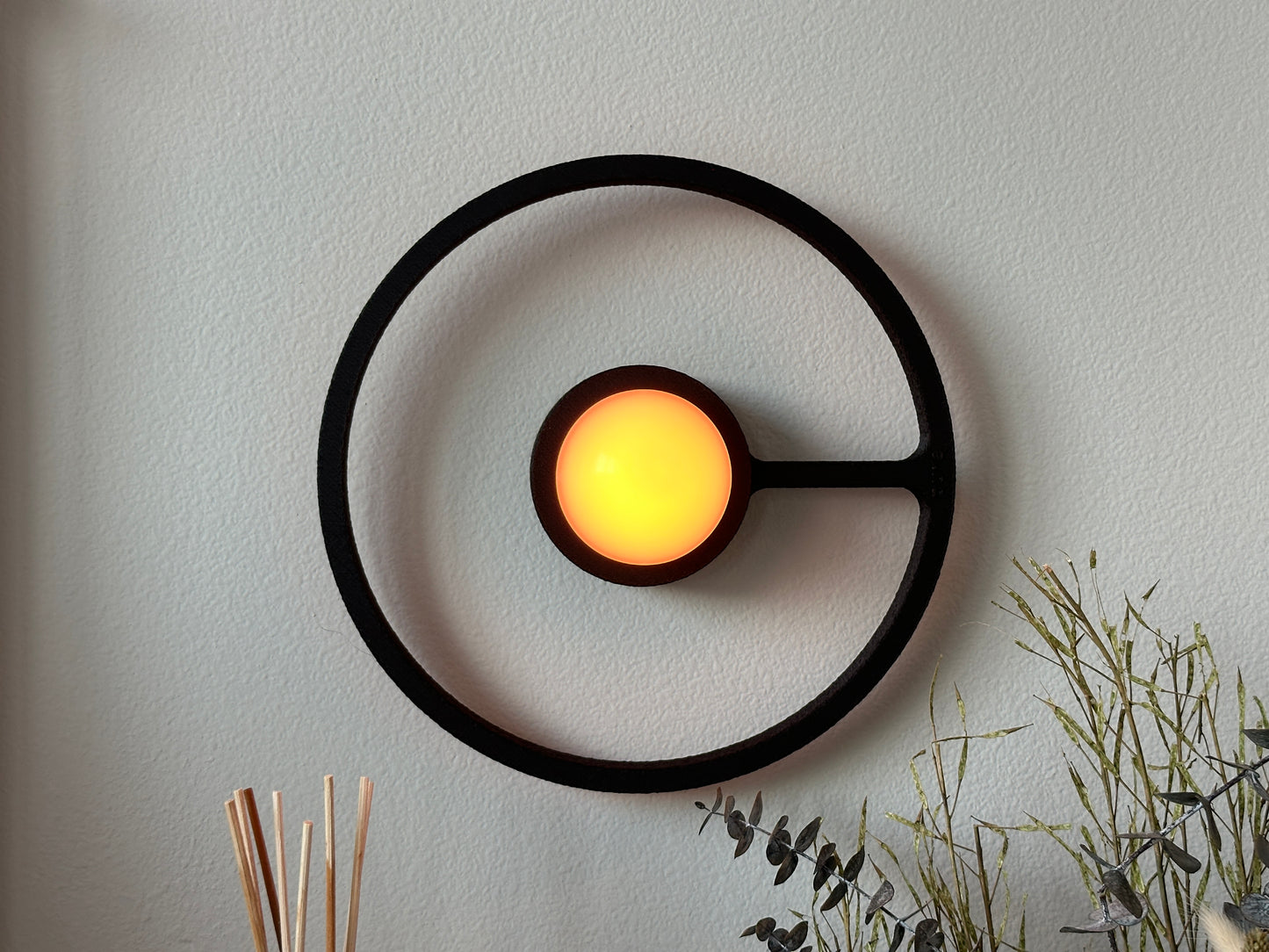 Pure MDRN ORA sconce in Black color on a bedroom wall next to a bed.