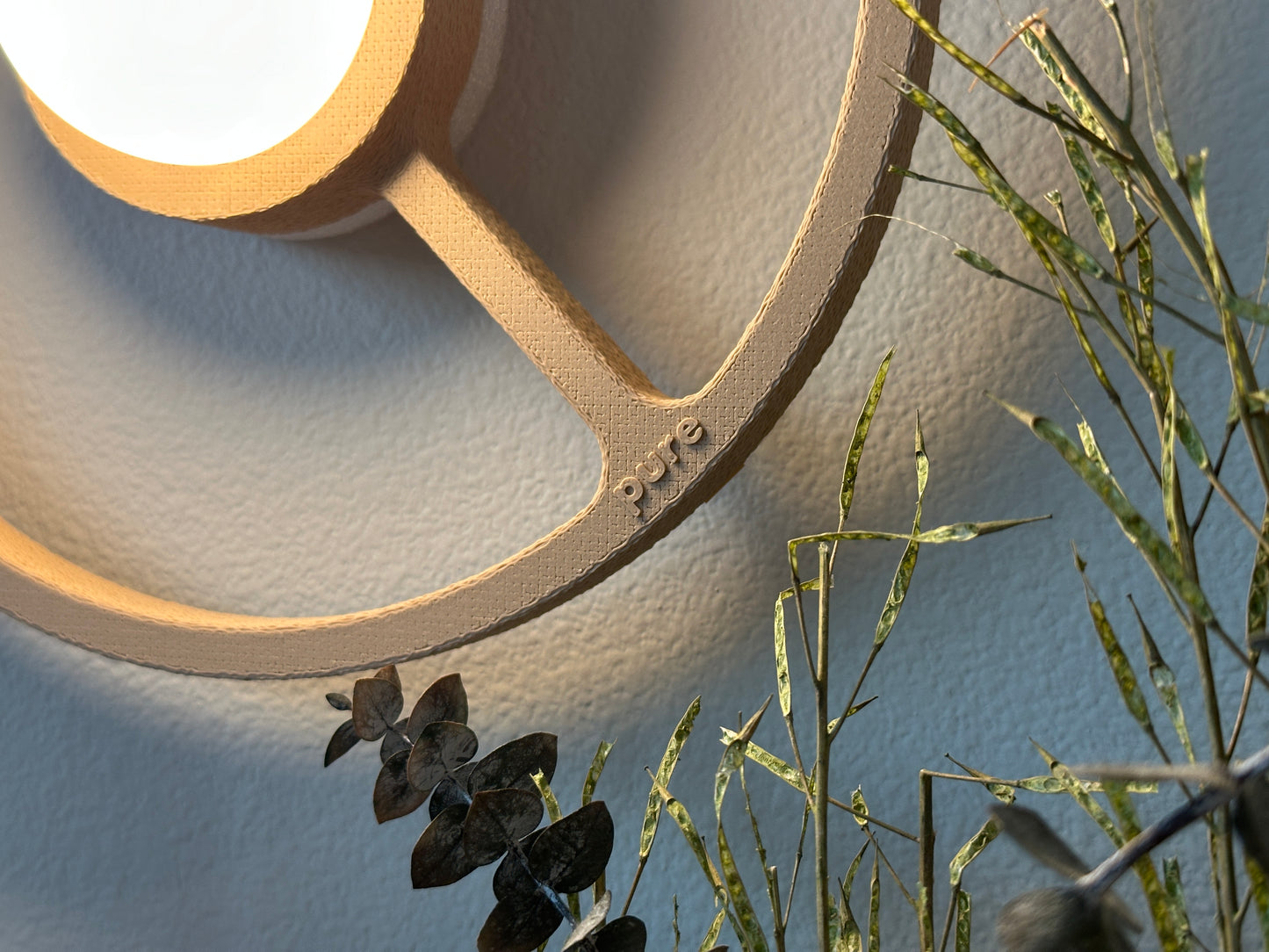 Close-up of the texture of the sand-colored ORA sconce on a bedroom wall providing warm accent light.