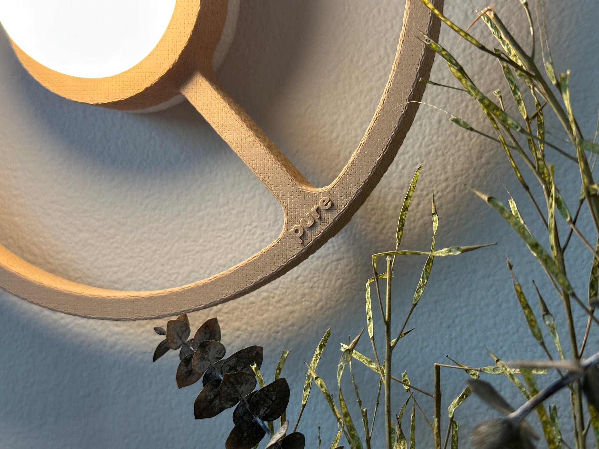 Close-up of the texture of the sand-colored ORA sconce on a bedroom wall providing warm accent light.
