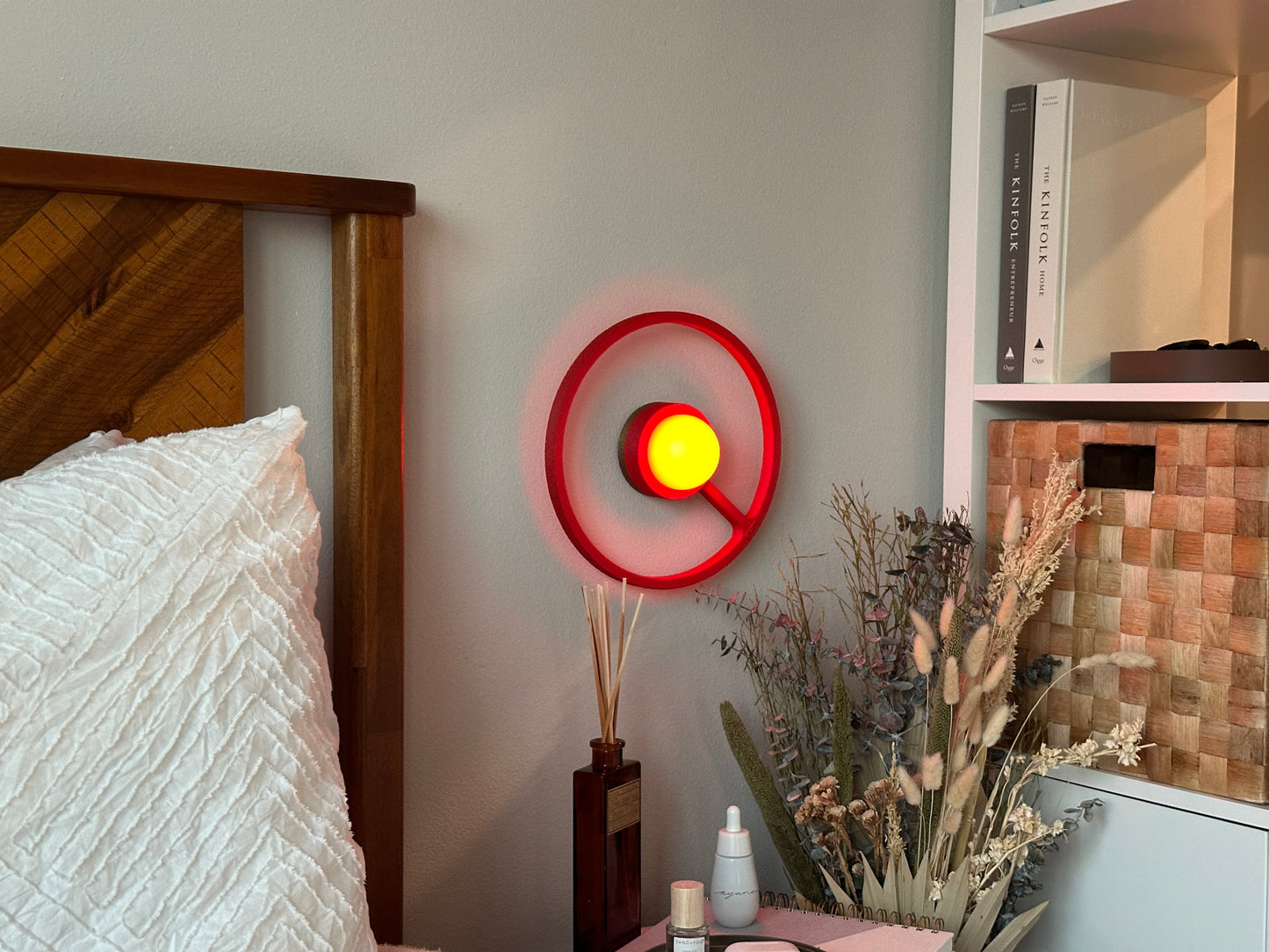 Cozy bedside picture of the crimson color way wireless ORA sconce by Pure MDRN