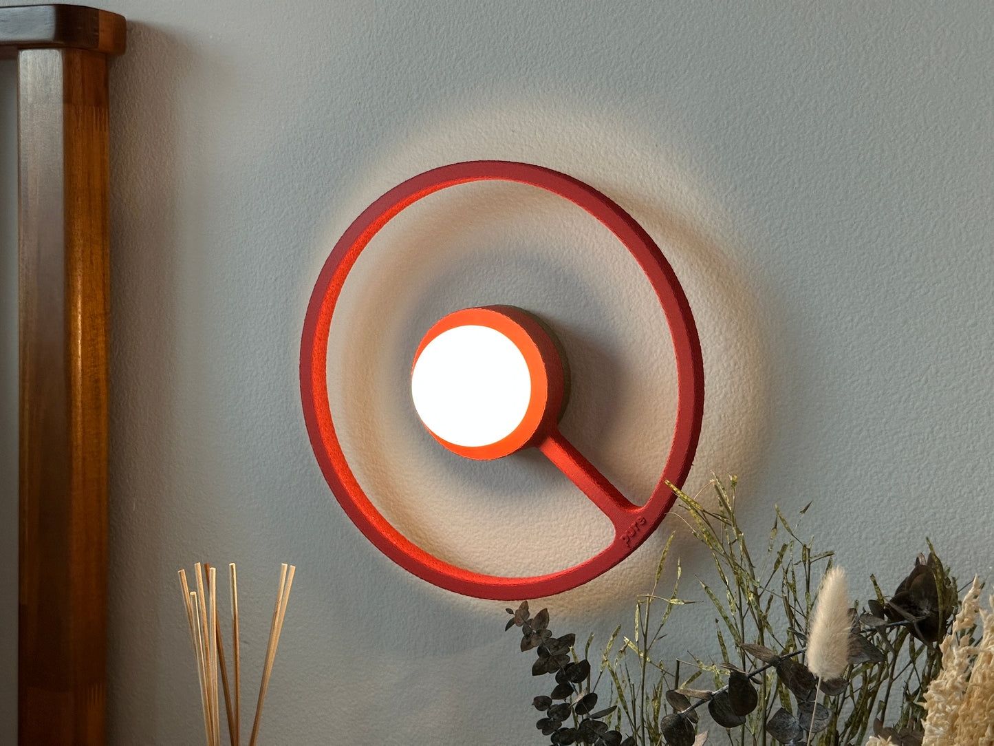 Cozy bedside picture of the crimson color way wireless ORA sconce by Pure MDRN