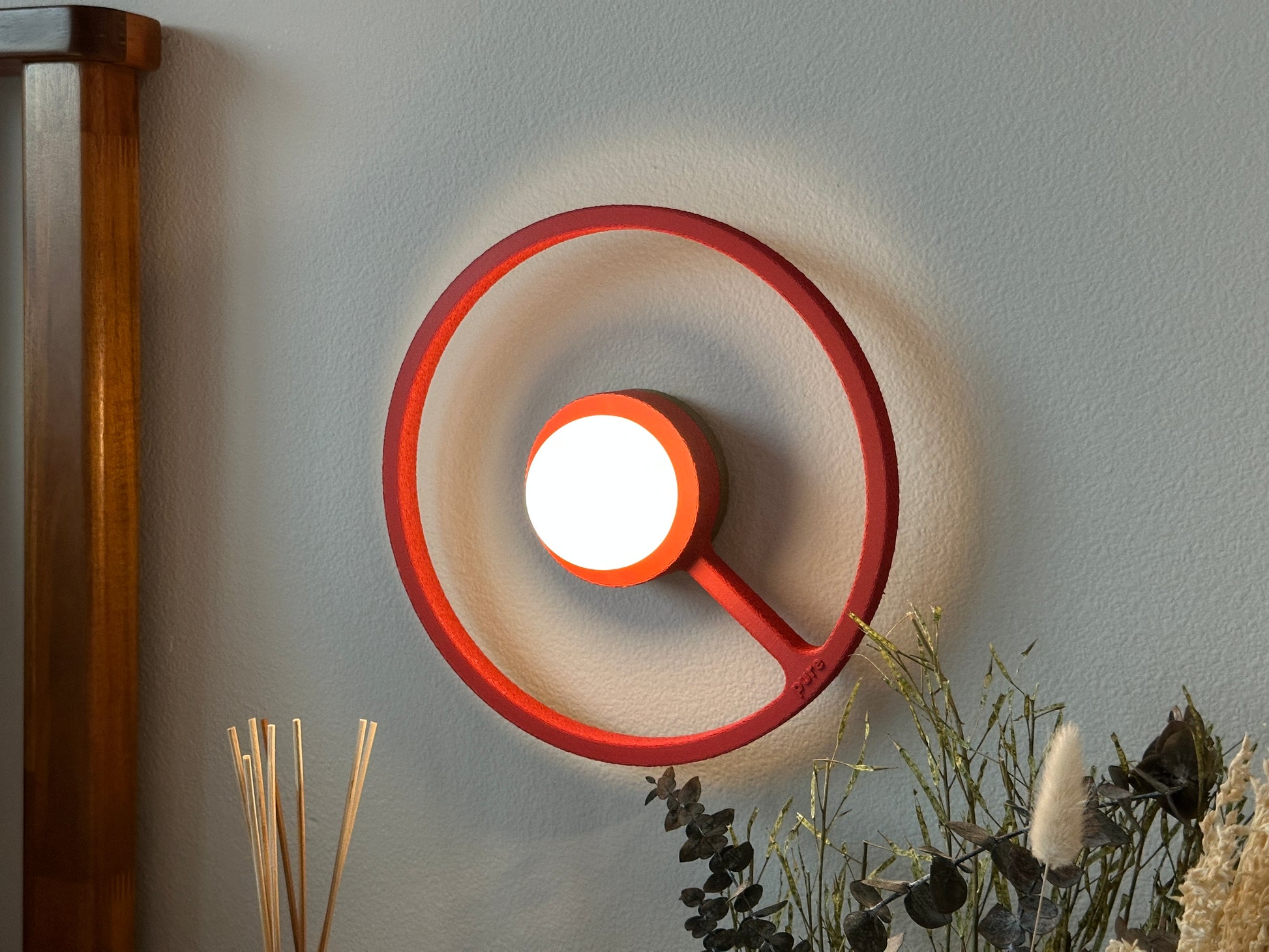 Cozy bedside picture of the crimson color way wireless ORA sconce by Pure MDRN