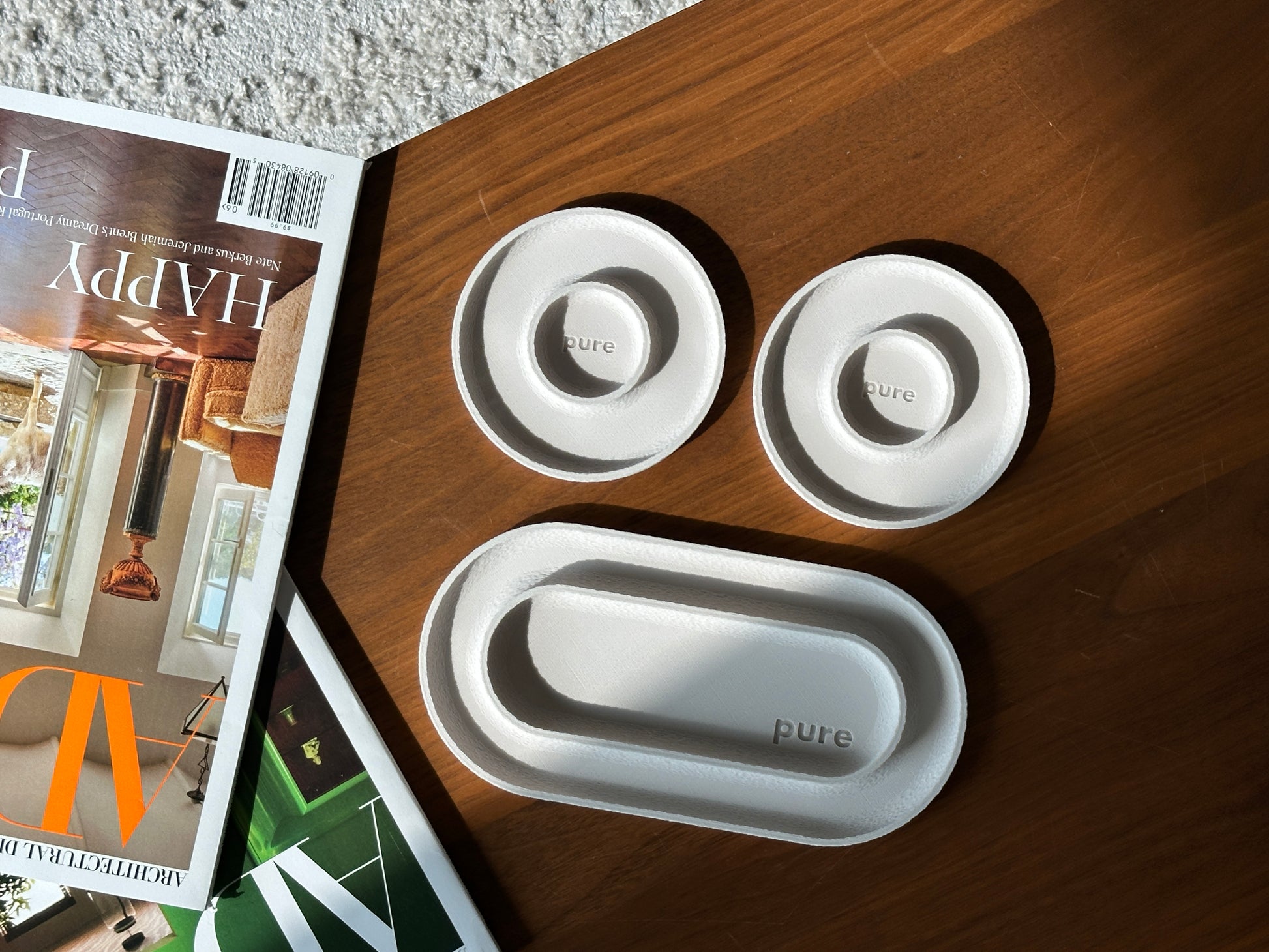 Cream white 3-piece valet tray set with long tray and two round ring dishes on a wood table.