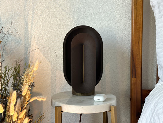 Turned off coffee brown statement lamp on a marble table, showing its matte textured finish and clean mid century modern silhouette.