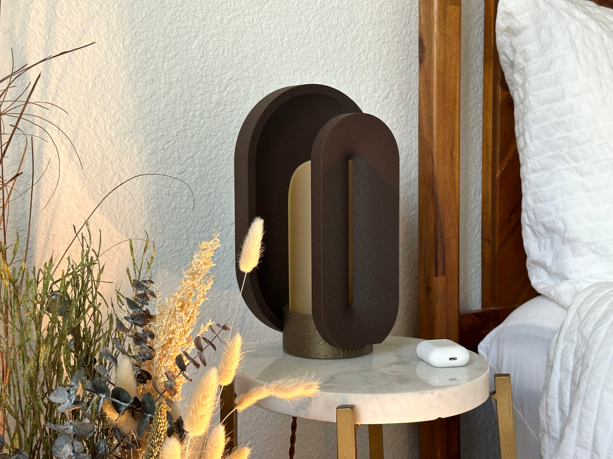 Angled view of the turned off coffee brown nightstand lamp, showing its curved outer shell and translucent inner light shield.