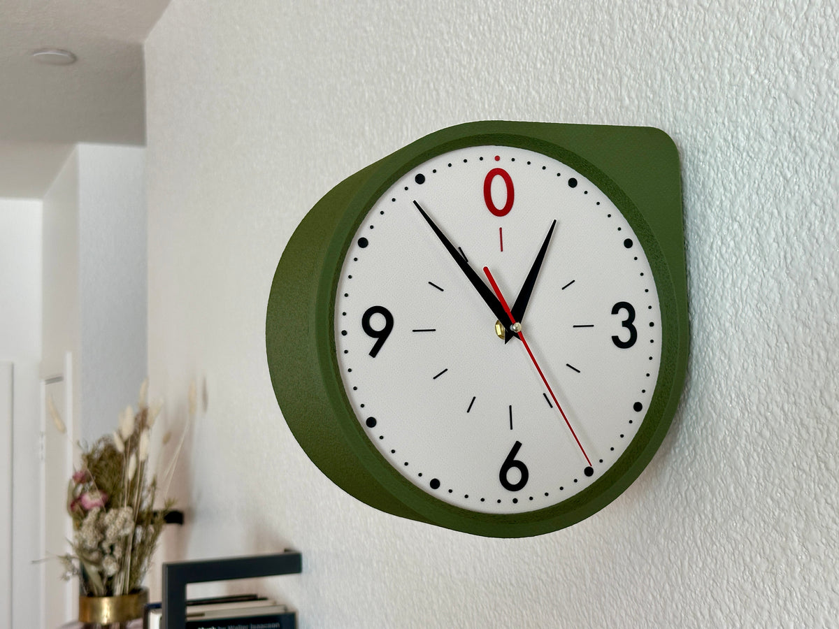 Moss Green double sided clock mounted on a white wall, featuring a warm illuminated dial and modern Mid Century clock design.