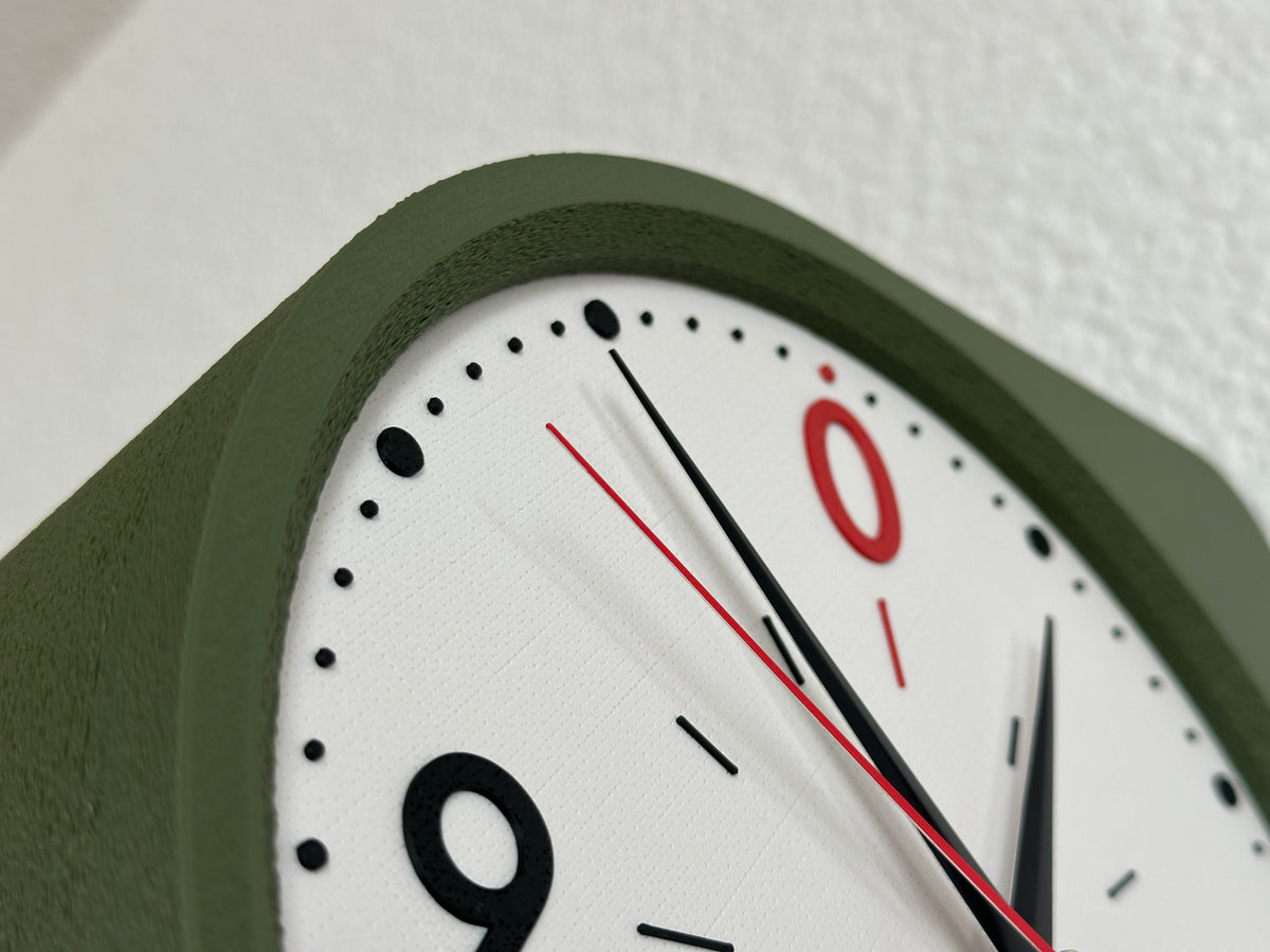 Close-up of the Cero modern wall clock showing the Moss Green textured body, red zero, black hands and detailed clock face.
