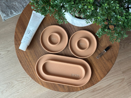 Set of valet trays on a wooden table with a plant in the background