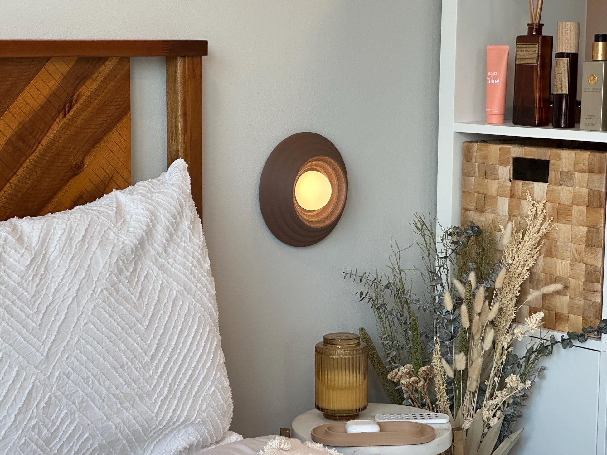 Wireless Circa scone wall lamp in a cozy bedside setting. Coffee color way.