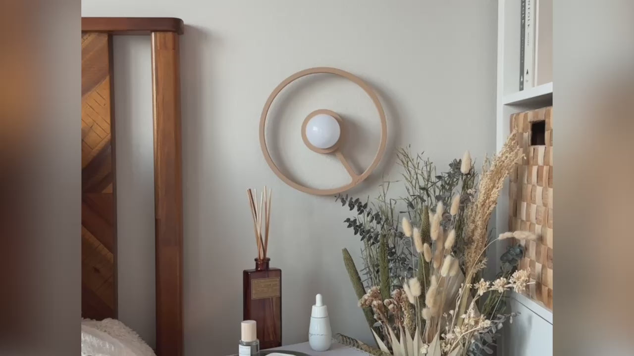 Pure MDRN ORA sconce in Sand color on a bedroom wall next to a bed.